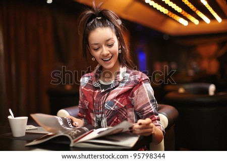 pretty thinking young woman sitting in the cafe read magazine with a cup of tea