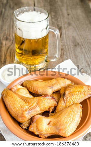 Smoked chicken wings with spicy sauce and glass of beer