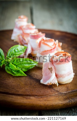 Rolled bacon strips on wooden board