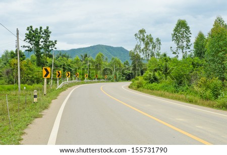 Countryside road with warning curve road sign