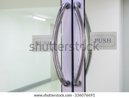 Glass door with chrome handles and push sign on door