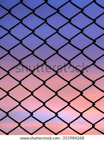 Silhouette mesh fence with sunset background