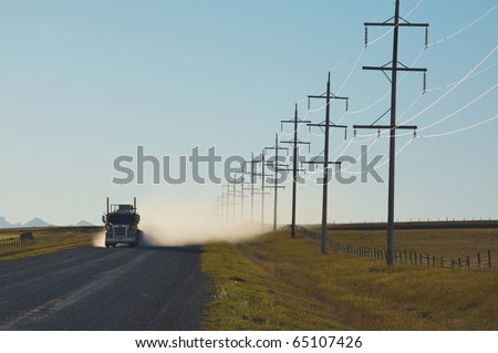 Sunlight on electrical power lines with truck on gravel road