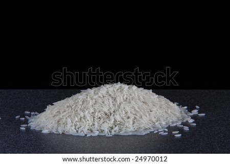 A neat pile of rice sitting on the worksurface in my kitchen, isolated on black