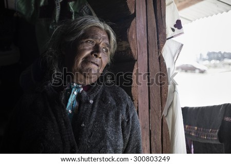 CHIAPAS, MEXICO - CIRCA DECEMBER 2013: Close up Old Poor Woman Leaning on the Wooden Wall While Looking Outside Through an Open Window and Thinking of Something.