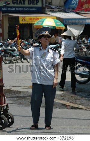 train crossing guard in her uniform directing street traffic in Hanoi, Vietnam