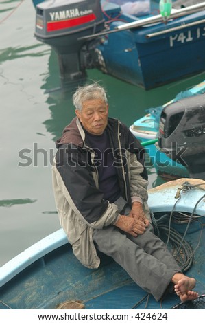 old fisherman selling his catch from his boat in Hong Kong