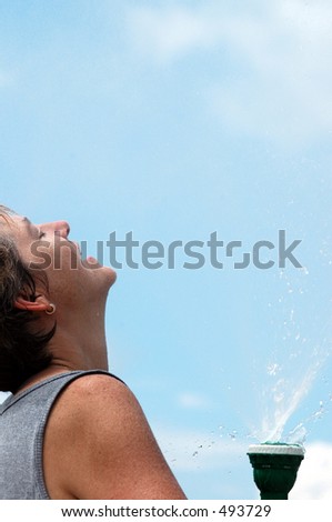 a hose pipe gushing water on a woman on a hot, sunny day