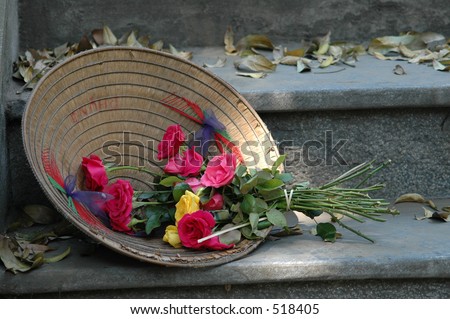 Flowers laying in a traditional vietnamese hat at the foot of a statute dedicated to Confucius