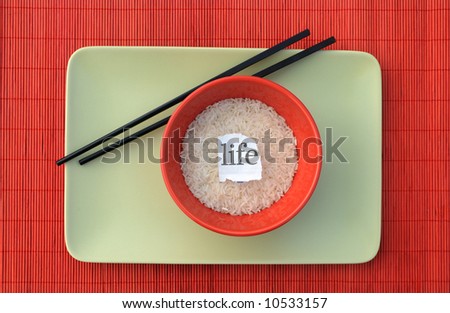 Bowl of rice, chopsticks, plate with text \