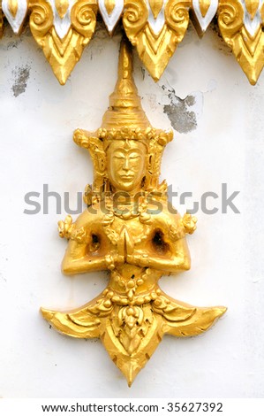 Golden temple God against a temple wall in Thailand