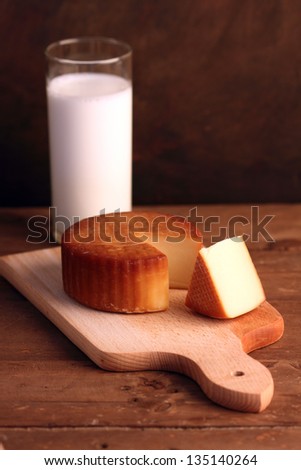 Yellow cheese on wooden board and a glass of milk