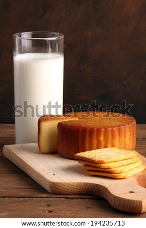 Yellow cheese, crackers and  glass of milk  on wooden board