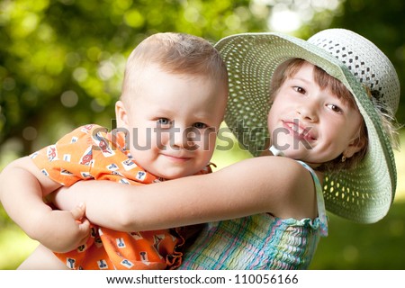 Girl holds in her arms her little brother