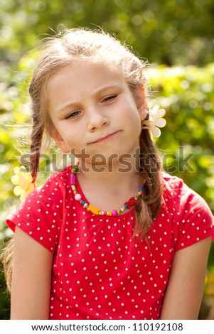 Sad little girl with pigtails in a red blouse