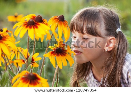 Cute girl with pleasure smell the wildflowers