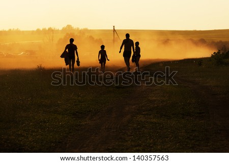 Company of adults and children walking on a country road at night