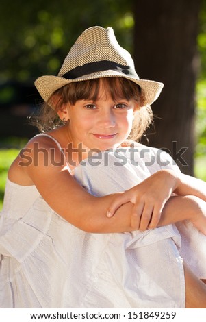 Merry brown-eyed girl in a stylish hat and dress