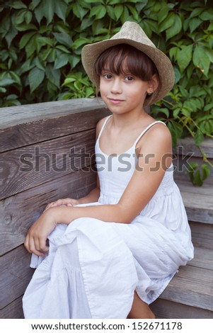Cute little girl in a hat sitting on the porch