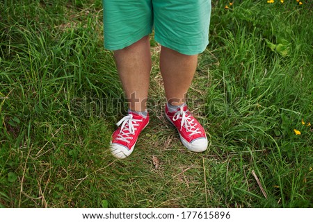 Legs men dressed in red sneakers on green grass