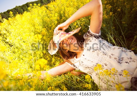 Happy woman lying among yellow wildflowers in summer