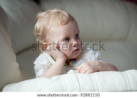 Little girl with a phone in thought settled on the couch