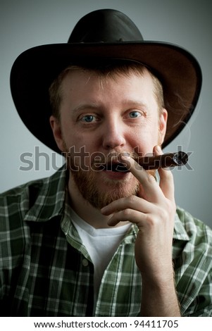 Red-bearded man in a cowboy hat and a shirt with a cigar in his mouth