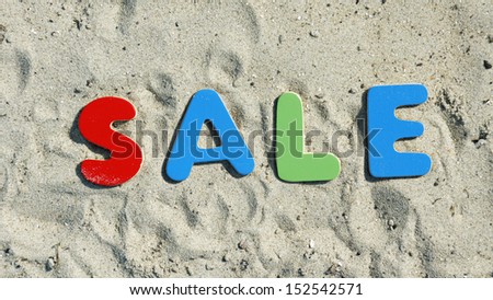 Sale in the summer written with sandy collered letters