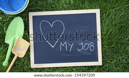 love my job written on a chalkboard between child toys