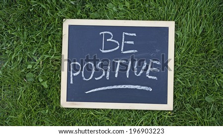 Be positive written on a chalkboard in the nature
