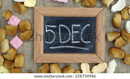 A chalkboard with the text 5 dec and a pile of Pepernoten, typical Dutch treat for Sinterklaas on 5 december
