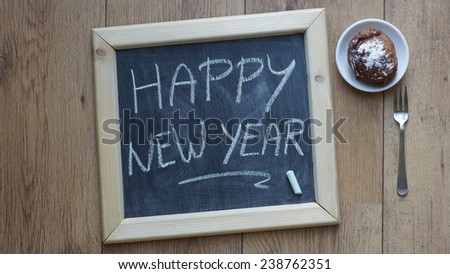 Happy new year written on a chalkboard next to a Dutch donut at the office