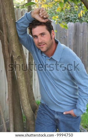 A man leaning against a tree