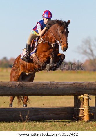 Young woman jumps a horse during practice on a cross country eventing course