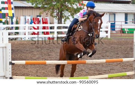 Young woman jumps horse in arena during a practice ride