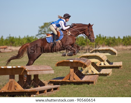 Teen rider jumps over an obstacle on a cross country course during a practice ride