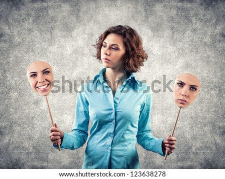 Two masks with different emotions in hands of the girl