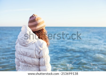 A young girl stand alone on the beach