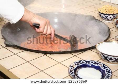 Preparation of rice with vegetables, the big pig-iron pan with the browned vegetables and nuts with the spices
