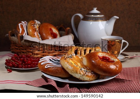 Still-life with a red currant fragrant tea and appetizing fresh rolls croissants and cheese cakes