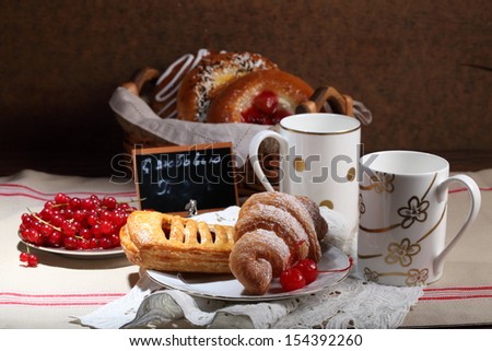 Appetizing cheese cakes with a stuffing from fresh berries and pies from flaky pastry on beautifully served table submitted with a fresh juicy ripe red currant