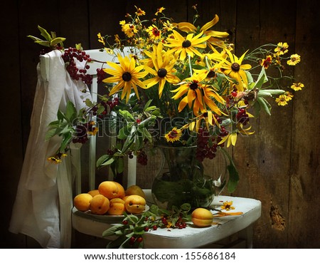 Still-life with apricots, ripe sweet appetizing apricots and a bright unusual bouquet from yellow colours and bird cherry branches
