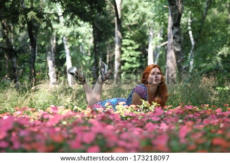 The young beautiful red-haired woman in beautiful park in the afternoon