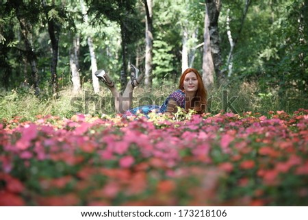 The young beautiful red-haired woman in beautiful park in the afternoon