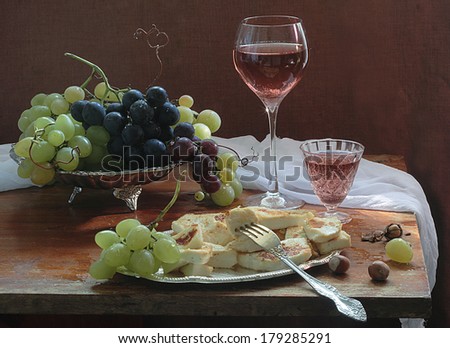Still-life with grapes and red wine, fresh juicy appetizing clusters of green both dark grapes and fragrant red wine in a graceful transparent glass