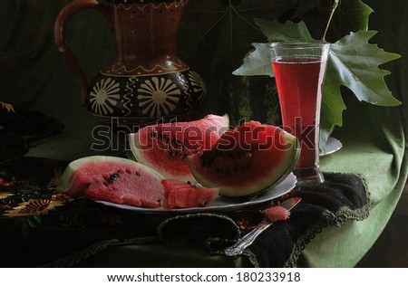 Still-life with a water-melon, a juicy ripe bright red water-melon and fresh sweet water-melon juice in a transparent glass