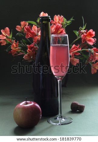 Still-life with a bright bouquet and pink wine, a bright spring bouquet and fragrant pink wine in a transparent graceful glass and a juicy sweet apple