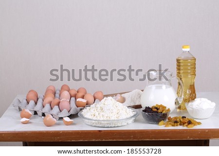 Still-life with fresh cottage cheese eggs and sour cream and dried fruits and milk, a flour and fresh cottage cheese with sour cream and eggs and dried fruits for preparation of a celebratory pie