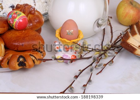 Easter still-life, branch of a willow and roll of a house batch, house rolls from fancy pastry both boiled eggs and milk in a transparent jug and a willow branch