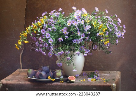 Still-life with a magnificent bouquet from bright autumn colours and a sweet ripe fig